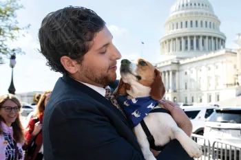 Man holding a beagle in front of the Capitol building in Washington, D.C.