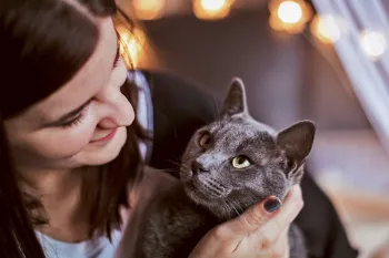 A woman cuddles with her cat who is looking at her adoringly.