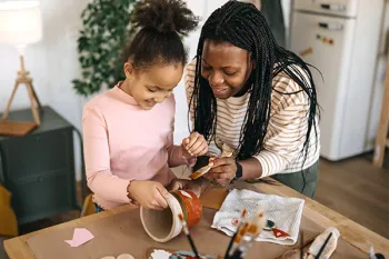 Woman and girl painting flower pots.