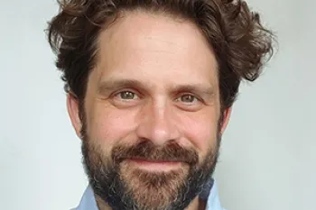headshot of a smiling man with dark hair
